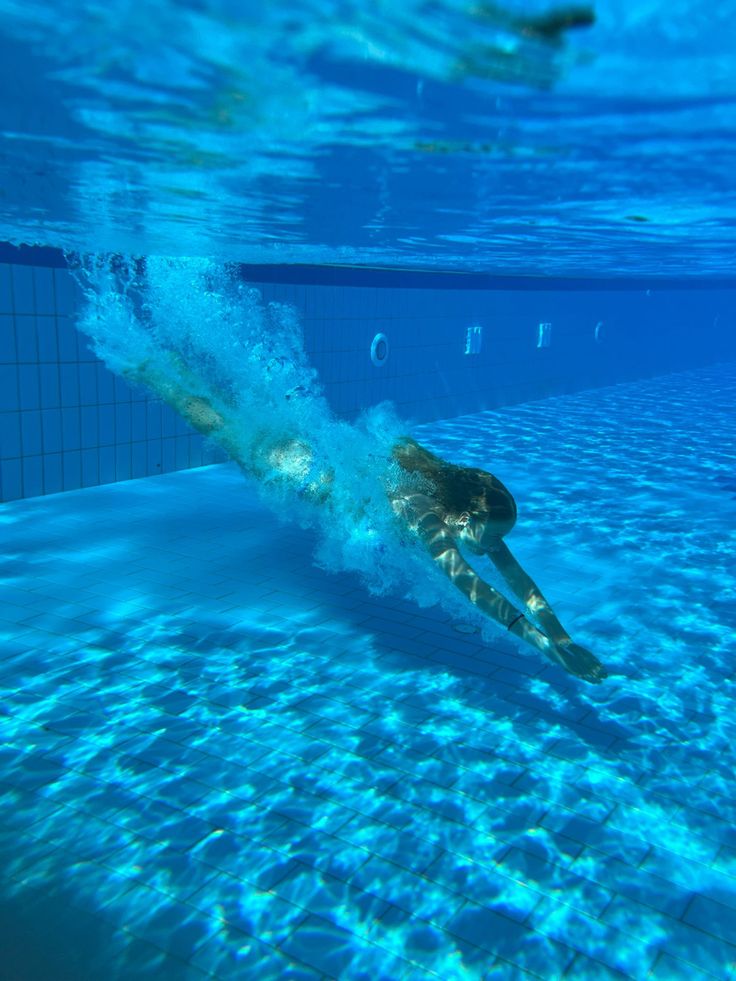 Swimmer underwater in a bright, clear pool